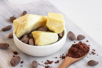 Cocoa butter or Cocoa bean solid oil and raw cocoa beans on rustic backdrop, healthy natural oil