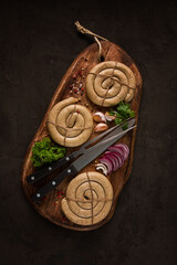 Raw spiral sausages, on a wooden board, top view, with spices, no people