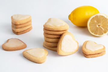 On a white table are stacks of heart shaped cookies and a lemon in the background.