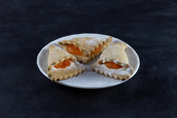 On the table are a white plate with cookies. On a dark background. Horizontal frame.