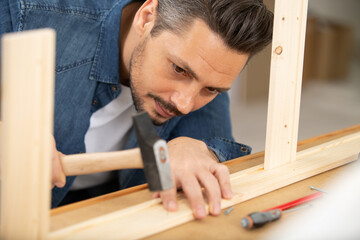 close up of hammering a nail into wooden board