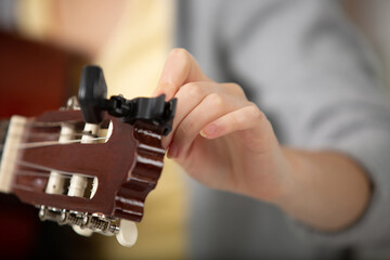 Obraz na płótnie Canvas detail of guitar being tuned by woman