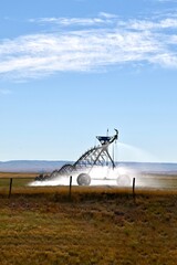 a large irrigation system on wheels waters a farm field