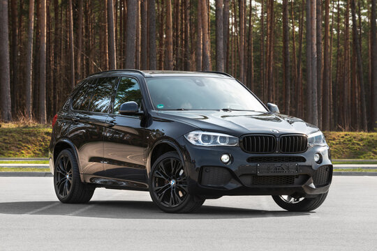 Switzerland, Bern - APRIL 23, 2021. Black BMW X5 F15 M, 3,0 L Turbo diesel, 280 Kw (381 h.p.), 2016 year model. Sport SUV. Car on black rims. Car on parking place near forest. Front side view.