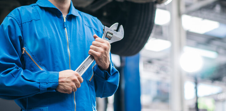 Mechanic hand holding wrench equipment tool in auto repair garage. checking car damage broken, repairing vehicle business. motor technician maintenance after service, copy space