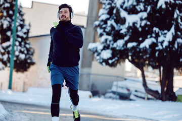 Below view of sportsman jogging on street on winter day.