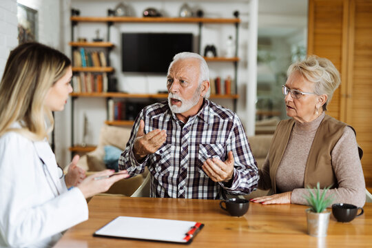 Worried senior couple communicating with their female nurse at home