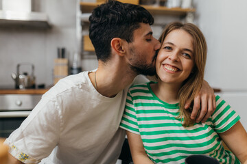 Man is kissing his girlfriend on the cheek - obrazy, fototapety, plakaty