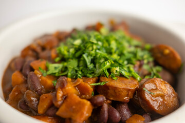 plate of Mexican beans prepared with sausage and bacon, chili and garnished with parsley