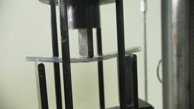 Press presses little polycarbonate sheet in laboratory. Testing of stability and flexibility of products at plant of innovative plastic materials closeup