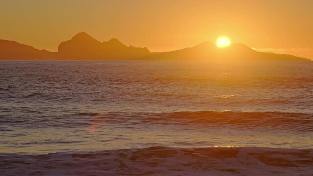 Sunrise over Stormy Sea. Shining Golden Waves with Sun Reflection at Sunset. Amazing light over Icelandic Coastline. Sharp Volcanic Cliffs. Atlantic Ocean Water. Iceland. Shot in 8K Resolution 4320p