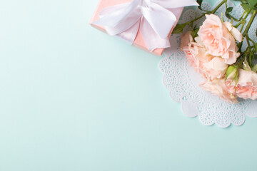 A gift with a bouquet of flowers on a light blue background. Banner for Valentine's Day.