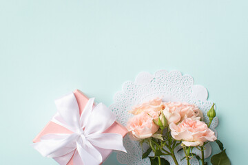 A gift with a bouquet of flowers on a light blue background.