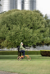 A man rides a bicycle to work against the backdrop of a green city. Bicycle environmentally friendly transport in the city.
