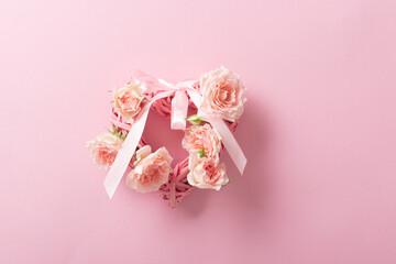 Valentine made of braided hearts and roses for Valentine's Day on a soft pink background. Minimalism, creativity, idea.