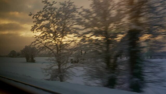 Paysage enneig&eacute; qui d&eacute;file &agrave; travers la fen&ecirc;tre d'un train en plein hiver