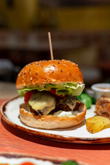 Organic vegetarian burger with plant based falafel balls, vegan cheese, green lettuce and baked potatoes