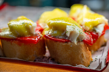 Typical snack of Basque Country, pinchos or pinxtos skewers with small pieces of bread, sea food, eggs, cheese, jamon served in bar in San-Sebastian or Bilbao, Spain