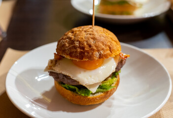 Tasty burger with white crispy ban, beef burger, egg, green lettuce and cheese