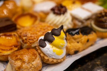 Delicious fresh baked colorful decorated cakes, tarts with cream and fruits on display in bakery in Bilbao, Basque Country, Spain