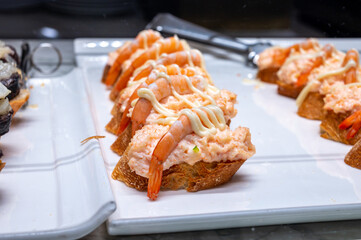 Typical snack of Basque Country, pinchos or pinxtos, small piece of bread with different fish and sea food toppings, served in bar in San-Sebastian or Bilbao, Spain