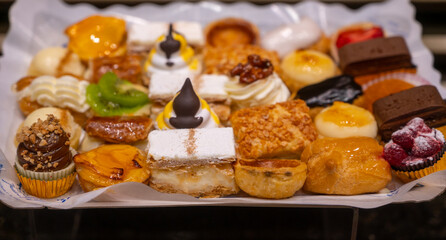Delicious fresh baked colorful decorated cakes, tarts with cream and fruits on display in bakery in Bilbao, Basque Country, Spain