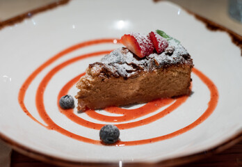 Delicious fresh baked colorful decorated vegan almond cake with fruits served in vegan restaurant in Bilbao, Basque Country, Spain