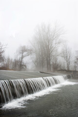 weir with waterfall in the morning fog,autumnal lanscape,