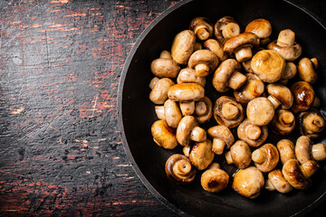 Fried small mushrooms in a frying pan. 