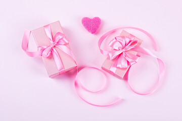 Happy Valentine's Day, Mother's Day and birthday greeting card. Knitted pink heart and gift boxes with a satin ribbon bow on a pink background