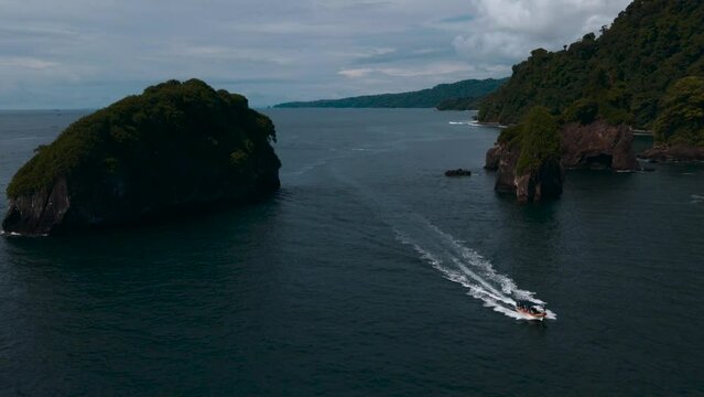 wide aerial view of small boat crossing the ocean on the colombian pacific coast of choco with islets in the background in the afternoon