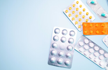 Tablets in blister and pills jar package on blue background.