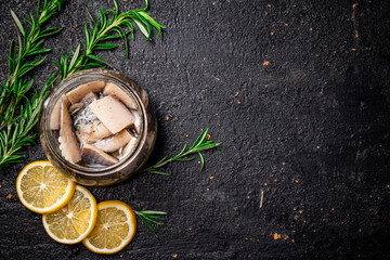 Pieces of salted herring in a jar with rosemary and lemon. 