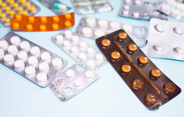 Tablets in blister and pills jar package on blue background.