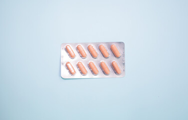 Tablets in blister and pills jar package on blue background.