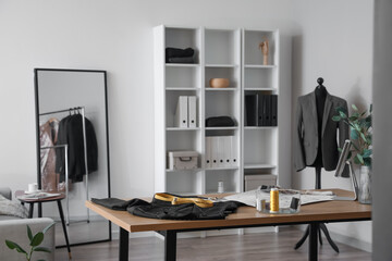 Tailor's workplace with clothes and supplies in modern atelier