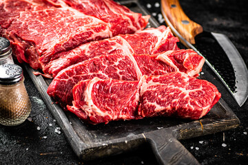 Raw beef on a cutting board with a knife. 