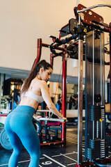 Fototapeta na wymiar Young couple is working out at gym. Attractive woman and handsome muscular man are training in light modern gym. Doing plank on kettlebell. Push-up on weights.