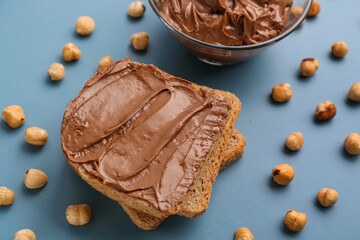 Tasty toasts with hazelnut butter and nuts on color background
