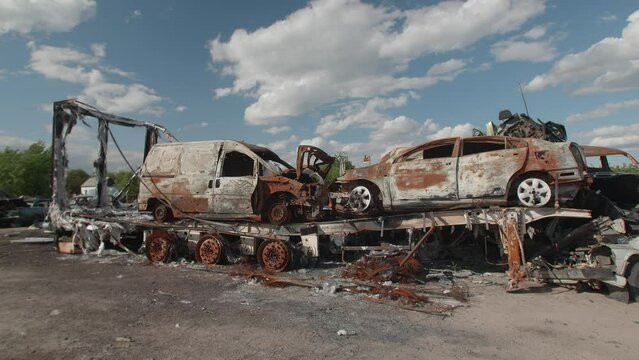 March, 2022. Bucha, Ukraine. Apocalyptic scene of car graveyard with abandoned landscape around. Blown-up cars for war background motion wallpaper. High quality 4k footage