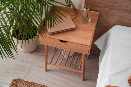 Wooden Bedside Table With Books And Reed Diffuser In Bedroom