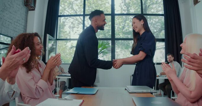 Happy multiracial business managers celebrate partnership with handshake, team applauding at office meeting slow motion.