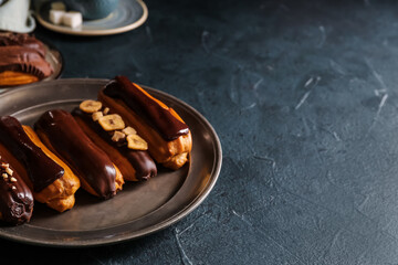 Plate of sweet chocolate eclairs on dark color background