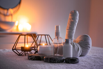 Spa composition with burning candles on couch in dark salon, closeup