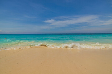 Beautiful view of sandy beach of Atlantic Ocean with incoming wave on shore. Aruba island.