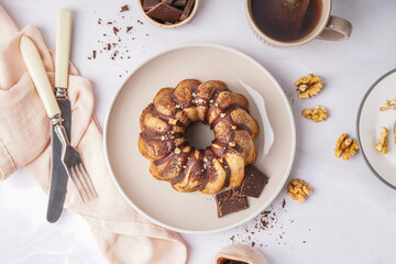 Plate with delicious cake, chocolate and walnuts on light background