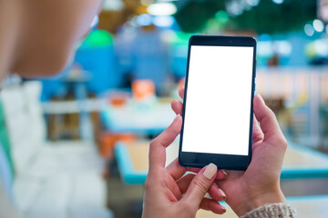 Mock up, white screen, copyspace, template, isolated, technology concept. Mockup image: woman looking at black smartphone mobile device with blank white display at cafe, restaurant - close up view