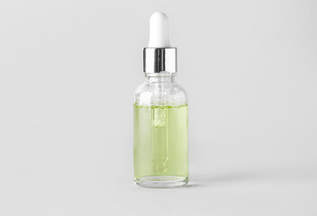 Glass bottle of natural serum on light background