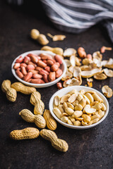 Unpeeled and peeled peanuts in bowl on kitchen table.