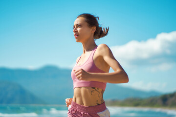 Sprinter run. Close up strong athletic woman running outdoors at seashore. Female doing intense...